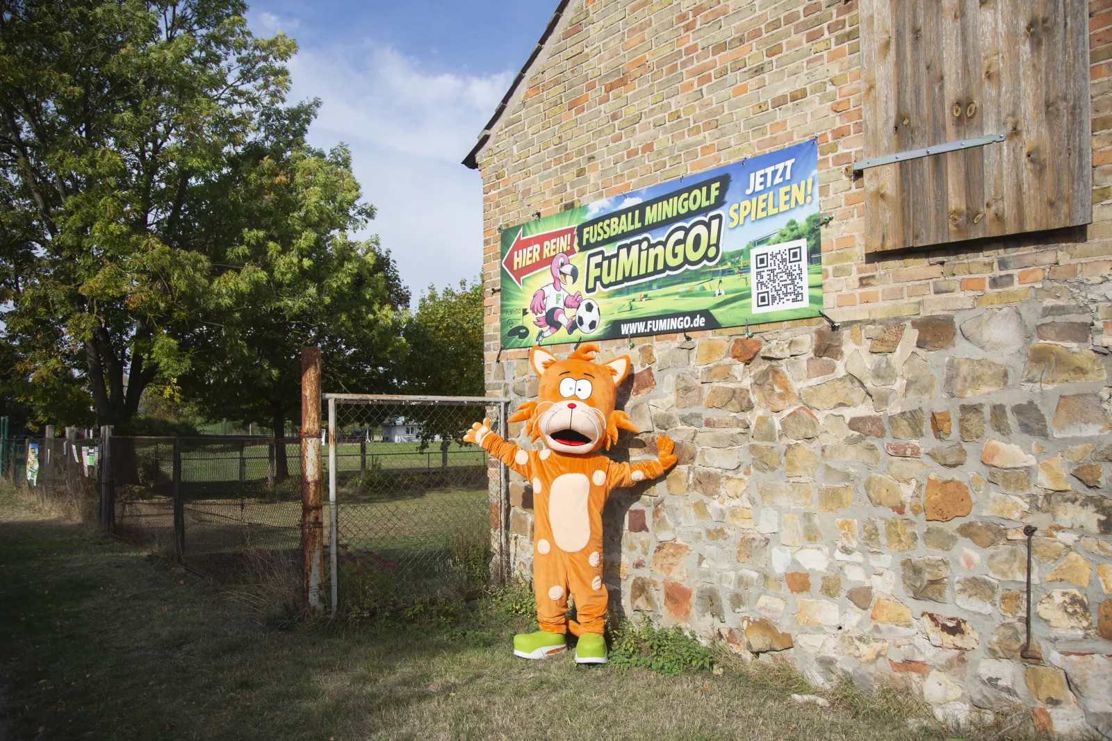 Das FuMinGo-Maskottchen vor dem Banner am Eingang der Anlage in Lübs